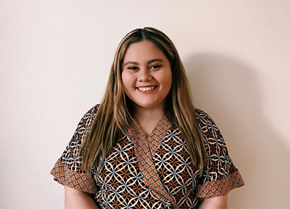 A headshot of Lorena Zelaya smiling.against a creme colored background.